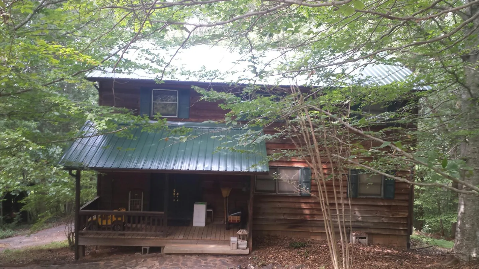 Green metal roof and covered porch on a log cabin in Tiffin