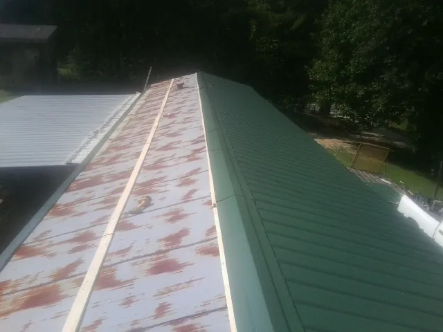 Old rusted panels beside newly installed green metal roofing — Wind Damage Roof Repair by Roofing Brothers in Tiffin