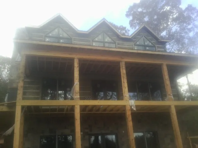 Dormers and porch framing on a large log home under construction — Roof Coating work by our crew in Tiffin