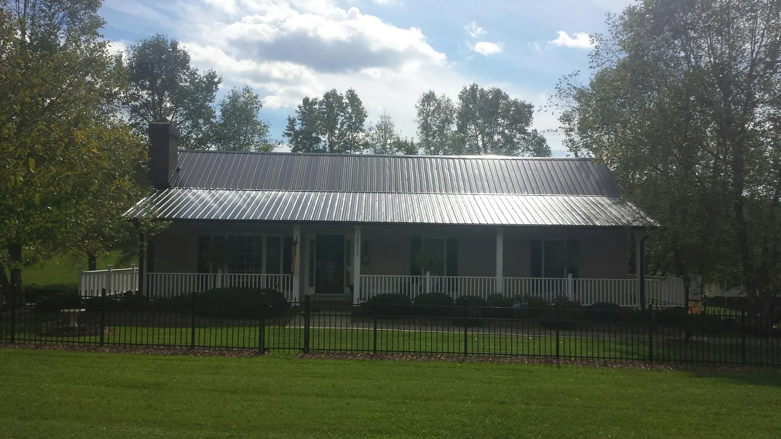 Gray metal roof on a brick ranch with a full width front porch — Gutter Guard Installation work by our crew in Tiffin