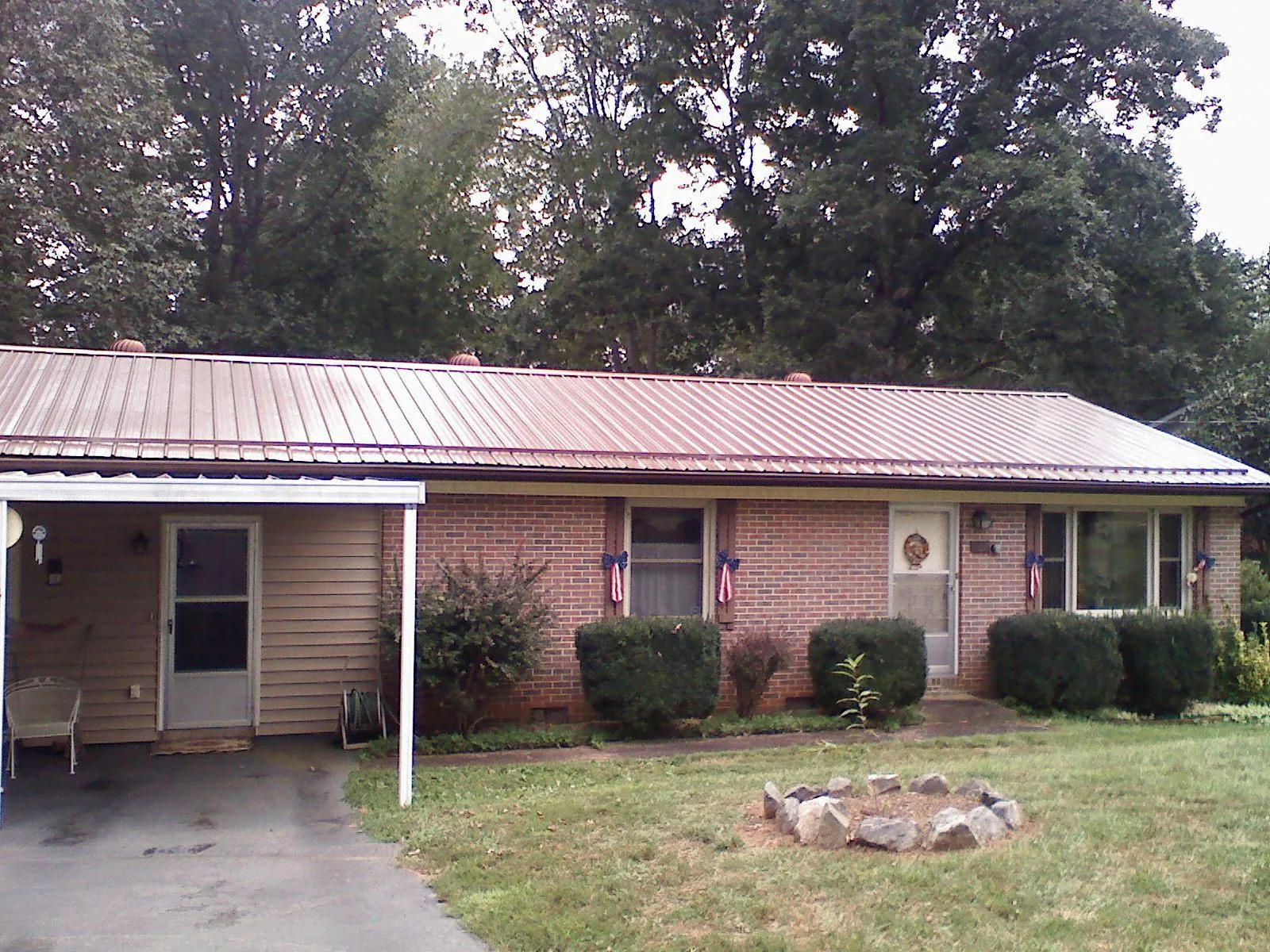 Bronze metal roof and carport on a brick ranch home — Roof Repair work by our crew in Tiffin